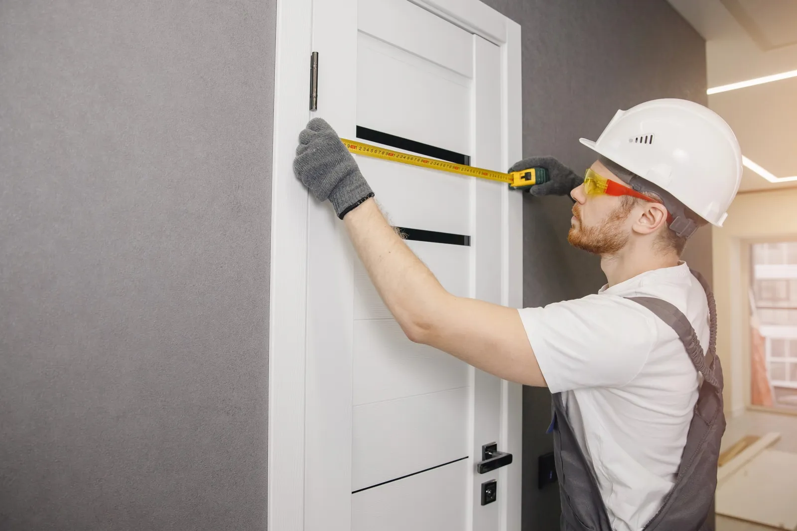 Prise de cotes au mètre ruban sur une porte avant remplacement de serrure