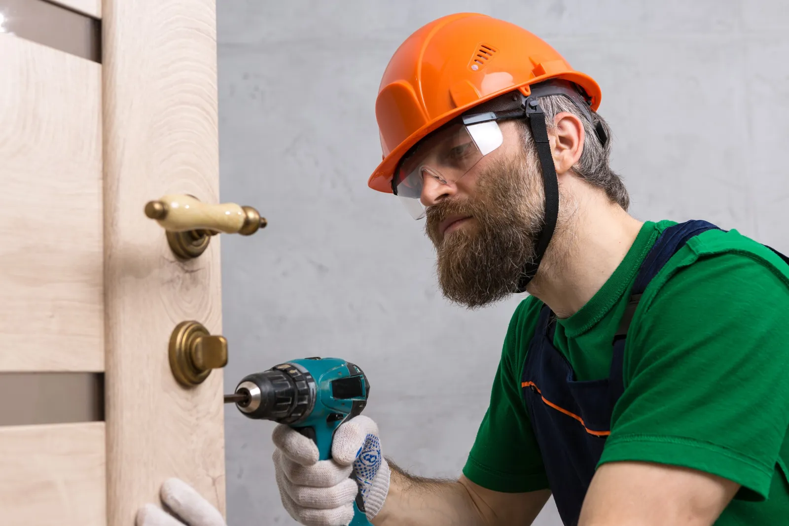 Artisan serrurier réglant la serrure d'une porte en bois chez un particulier